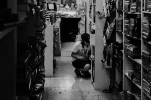 Estantes de librería con volúmenes de manga apilados y manos anónimas alcanzando los libros