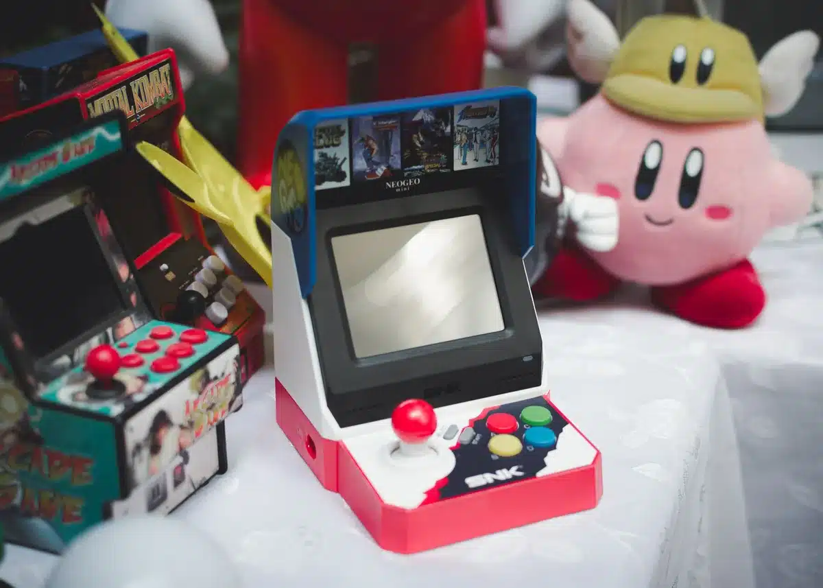 Vintage arcade cabinet with pixelated screen, joystick and red buttons, glowing neon trim, dark arcade hall setting