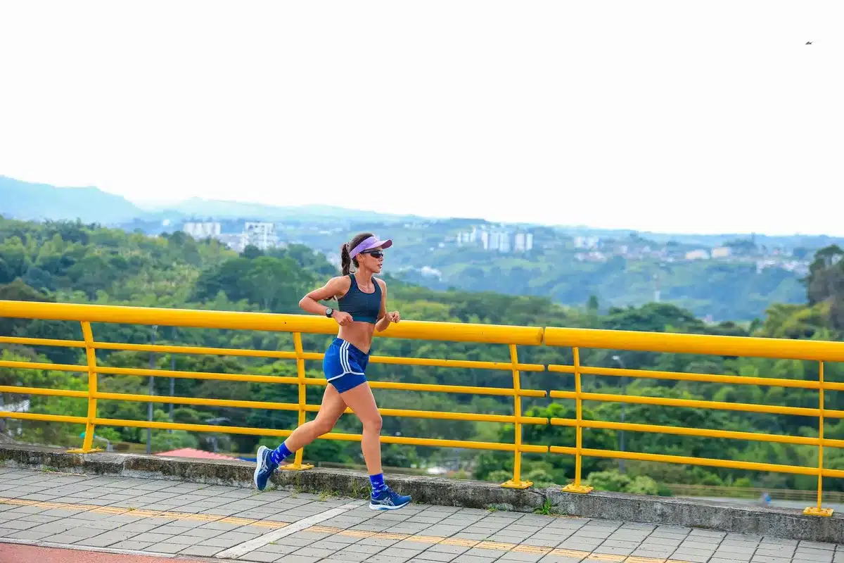 User wearing smartwatch during outdoor run, wrist raised against bright sky, fitness tracking in action