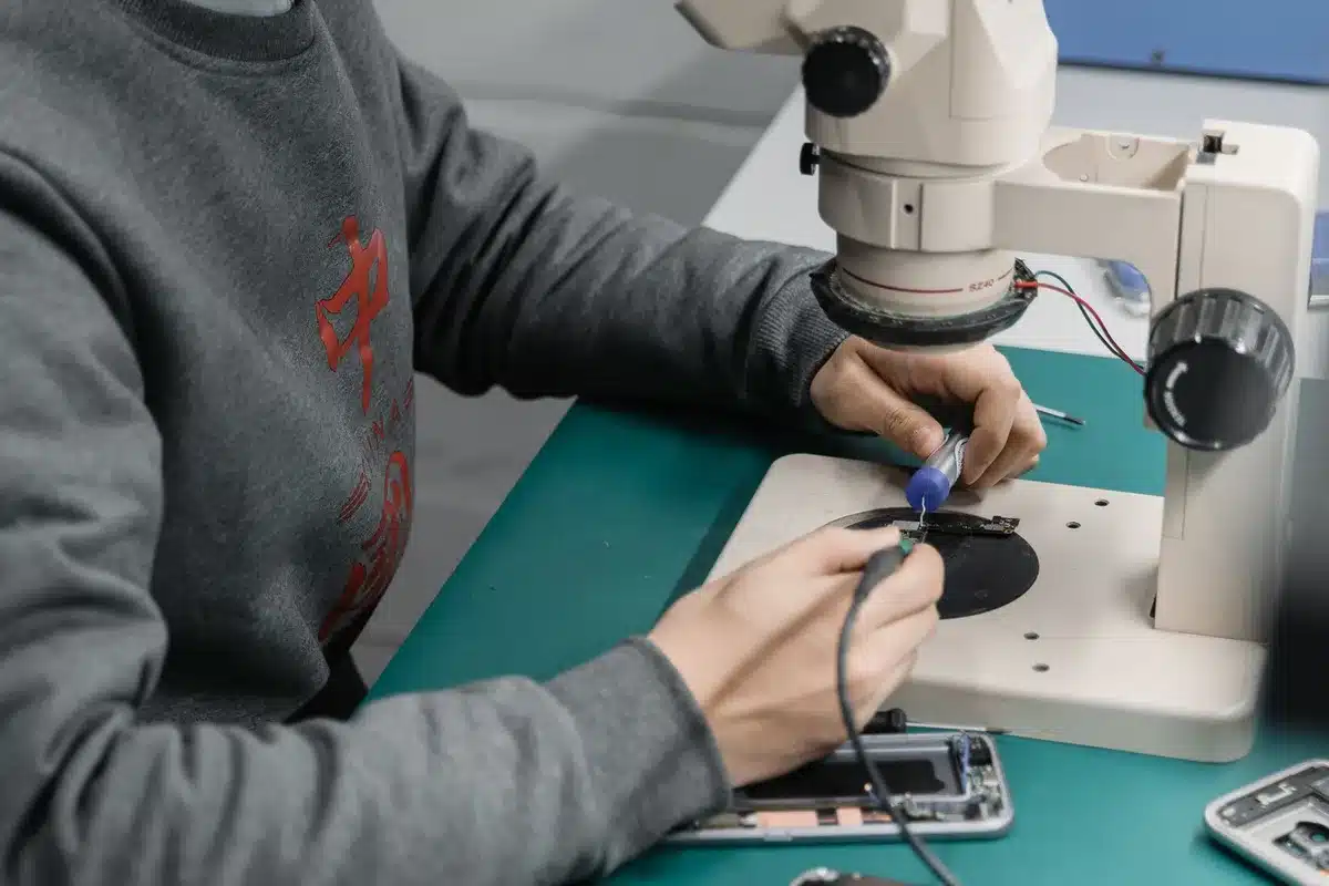 Técnico reparando un teléfono móvil en un taller con herramientas y piezas