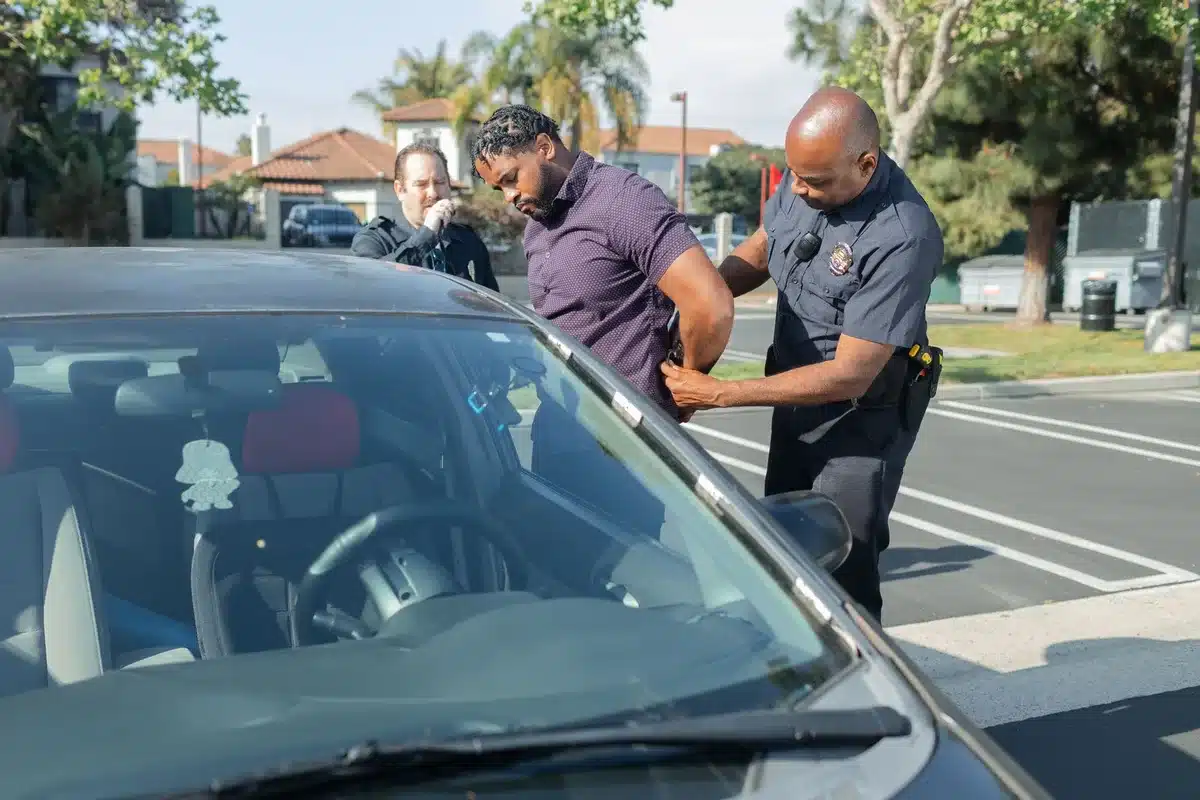 Police officer at a traffic stop with a driver showing documentation on a smartphone screen, neither person's face visible, daylight highway setting, focus on the phone display