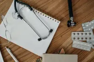 Páginas de manuscrito y estetoscopio sobre escritorio iluminado, evocando un thriller médico