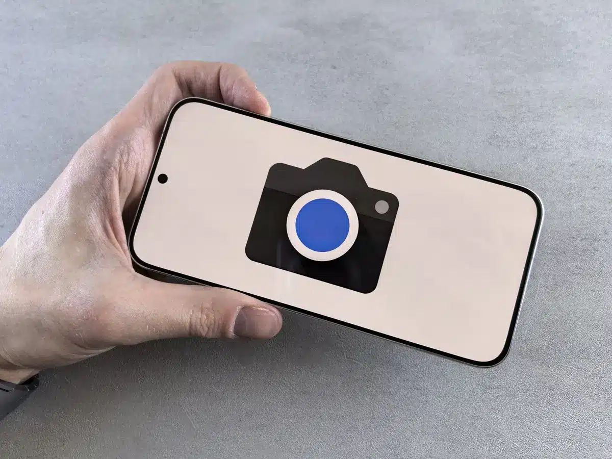 A sleek gray smartphone with a triple-camera module on the back sits on a white surface, catching natural light that highlights the device's slim 6.9mm profile and glossy finish.