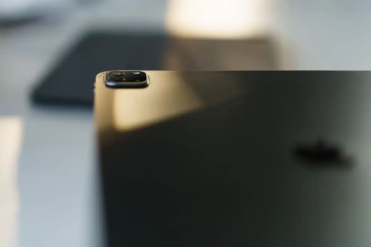 A close-up of a smartphone's triple-camera module mounted on the device's back, showing the arrangement of lenses and the OIS stabilization mechanism in detail.