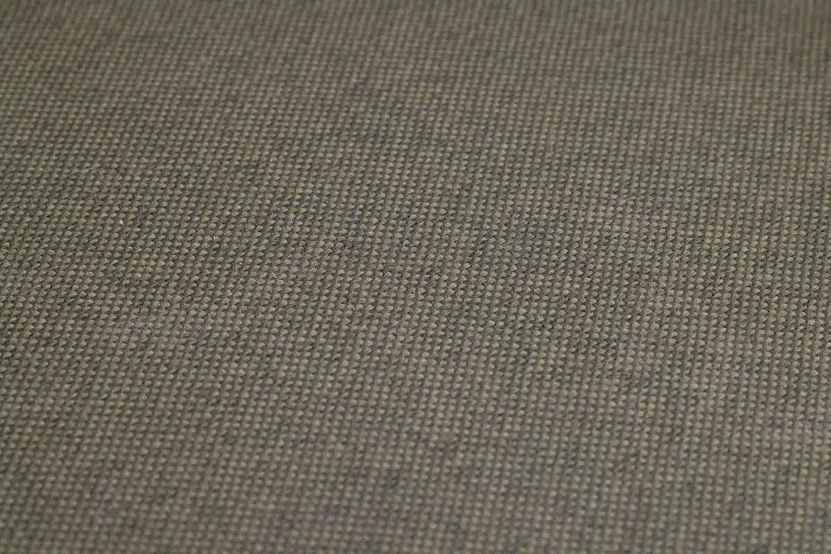 Close-up detail of gray polypiel upholstery texture on the sofa frame, showing the material quality and neutral tone against soft natural lighting