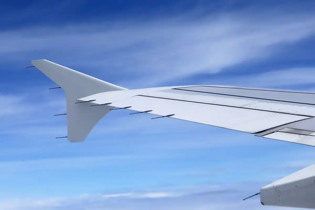 Satellite terminal mounted on aircraft fuselage, sleek metallic antenna catching sunlight against clear blue sky at cruising altitude, technological innovation in motion