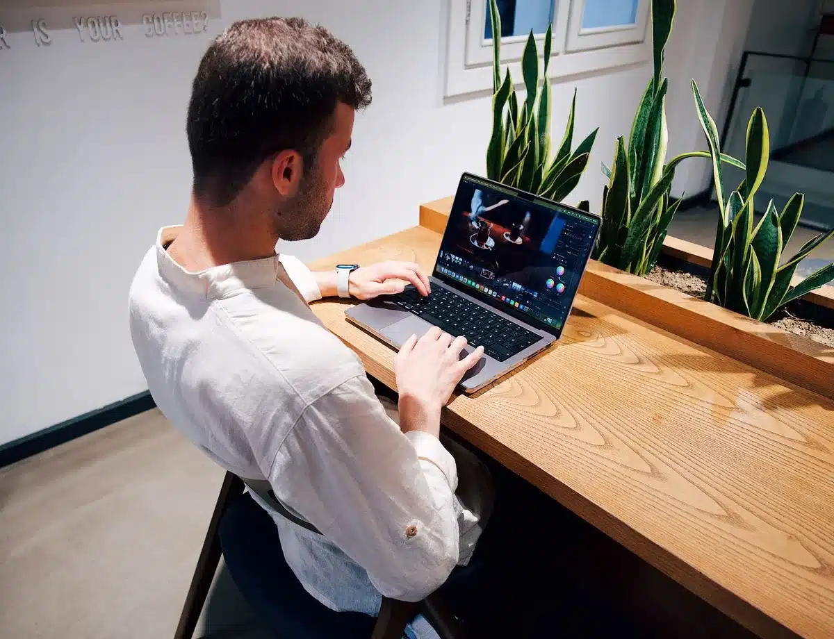 Empty display table with a sleek unbranded laptop, charger beside it on a wooden desk, blurred background of a modern living room