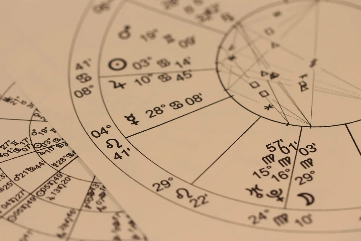 Close-up of an unbranded smartphone on a picnic blanket displaying constellation lines and planet labels in an app interface, no people visible