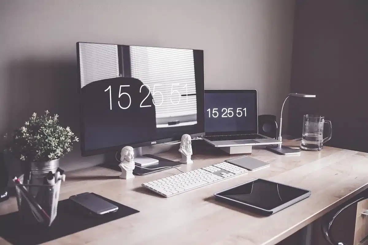 Compact silver desktop computer on a minimalist desk with a monitor, keyboard, and mouse, showing the small form factor and clean setup aesthetic of a modern workspace