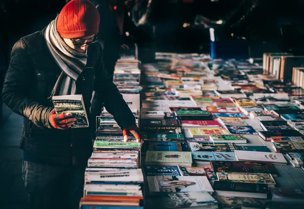 Estantería de manga en librería con lectores mirando volúmenes