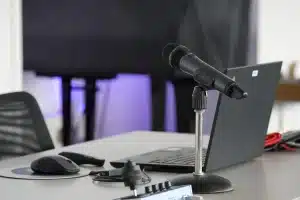 Manos con mando y auriculares frente a una pantalla que muestra arte anime borroso