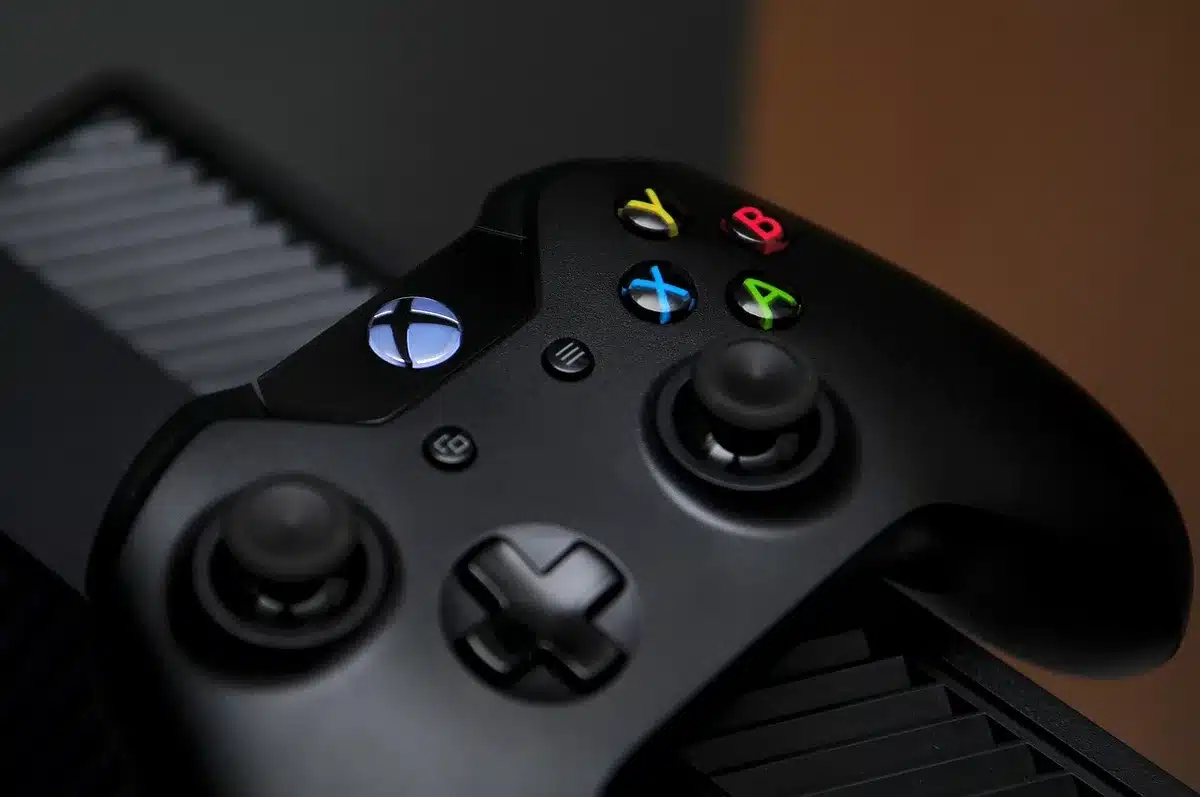 Gaming console in sleek, minimalist design shown against a gradient background with subtle circuit board patterns, soft ambient lighting.