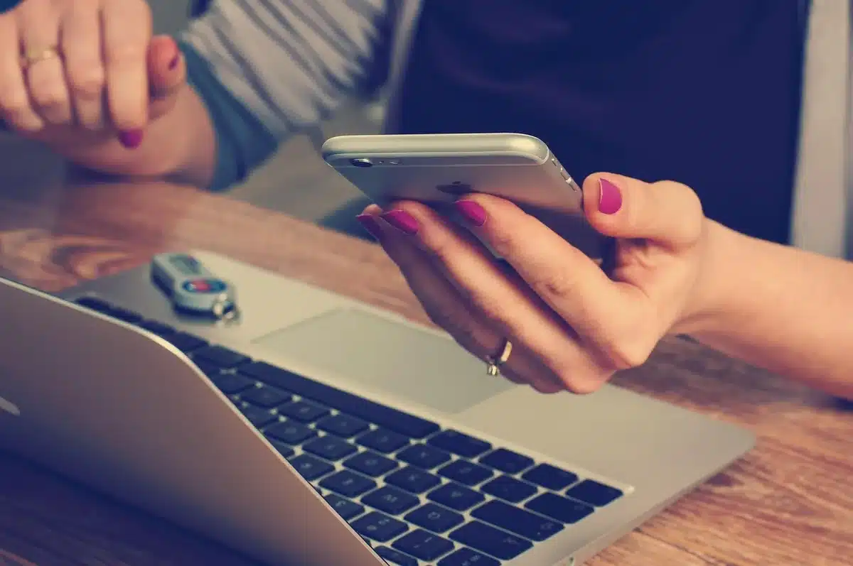 An anonymous hand holding an unbranded phone showing a battery icon at 75% on screen, neutral background
