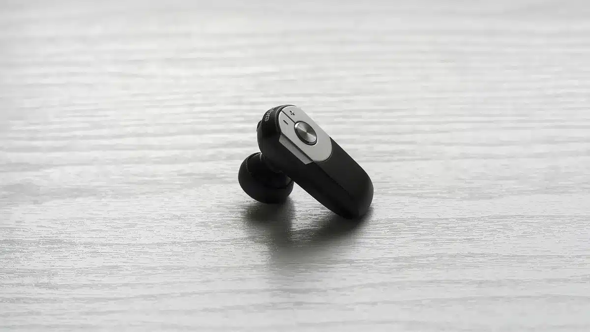 an empty retail shelf with boxed wireless earbuds on sale tags, a small price sticker visible but unreadable