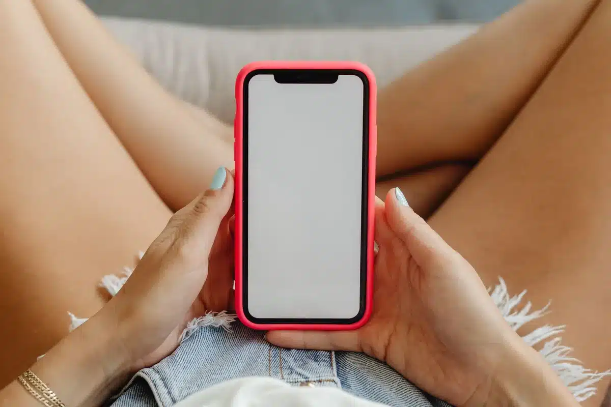 anonymous silhouette of a person looking at a phone screen in low light, network icons visible