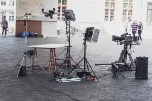 Set de rodaje vacío con claqueta y guiones sobre una mesa, siluetas de equipo al fondo