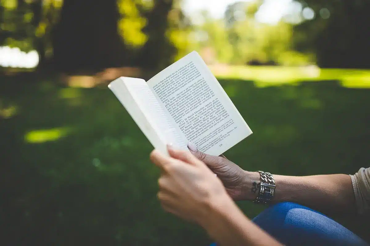 Anonymous hands holding a ceramic mug, an Apple Watch silhouette visible on the wrist, the watch screen blurred but glowing with data rings
