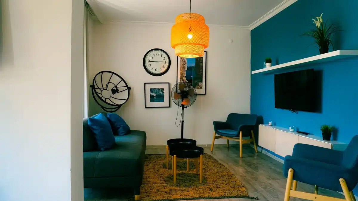 A minimalistic living room with a large TV showing a blurred fast-motion racing scene, no logos, distant anonymous viewer on sofa