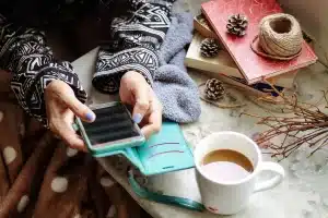 Manos anotando en una libreta sobre una mesa con café y papeles