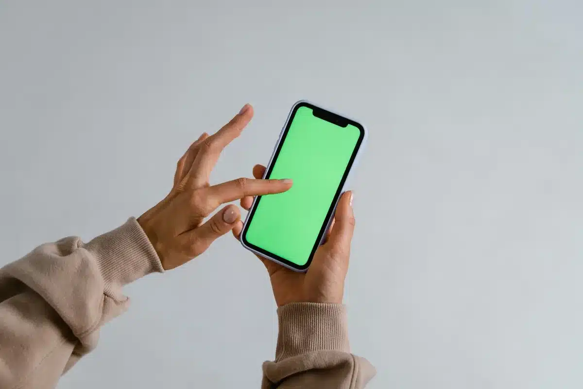 Anonymous hands holding a small, unbranded phone viewed from behind, thumb near the power button, blurred city background suggesting daily commuting use