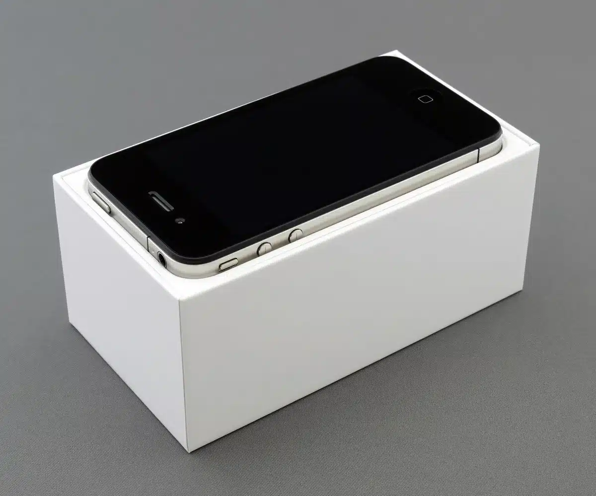 An empty retail shelf with several generic unbranded smartphone boxes, one box slightly pulled forward to suggest a newly updated model